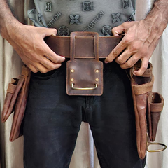 Person wearing a brown leather belt with tool pouches, holding one of the pouches open.