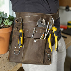 Person wearing a tool belt with various tools in a workshop setting