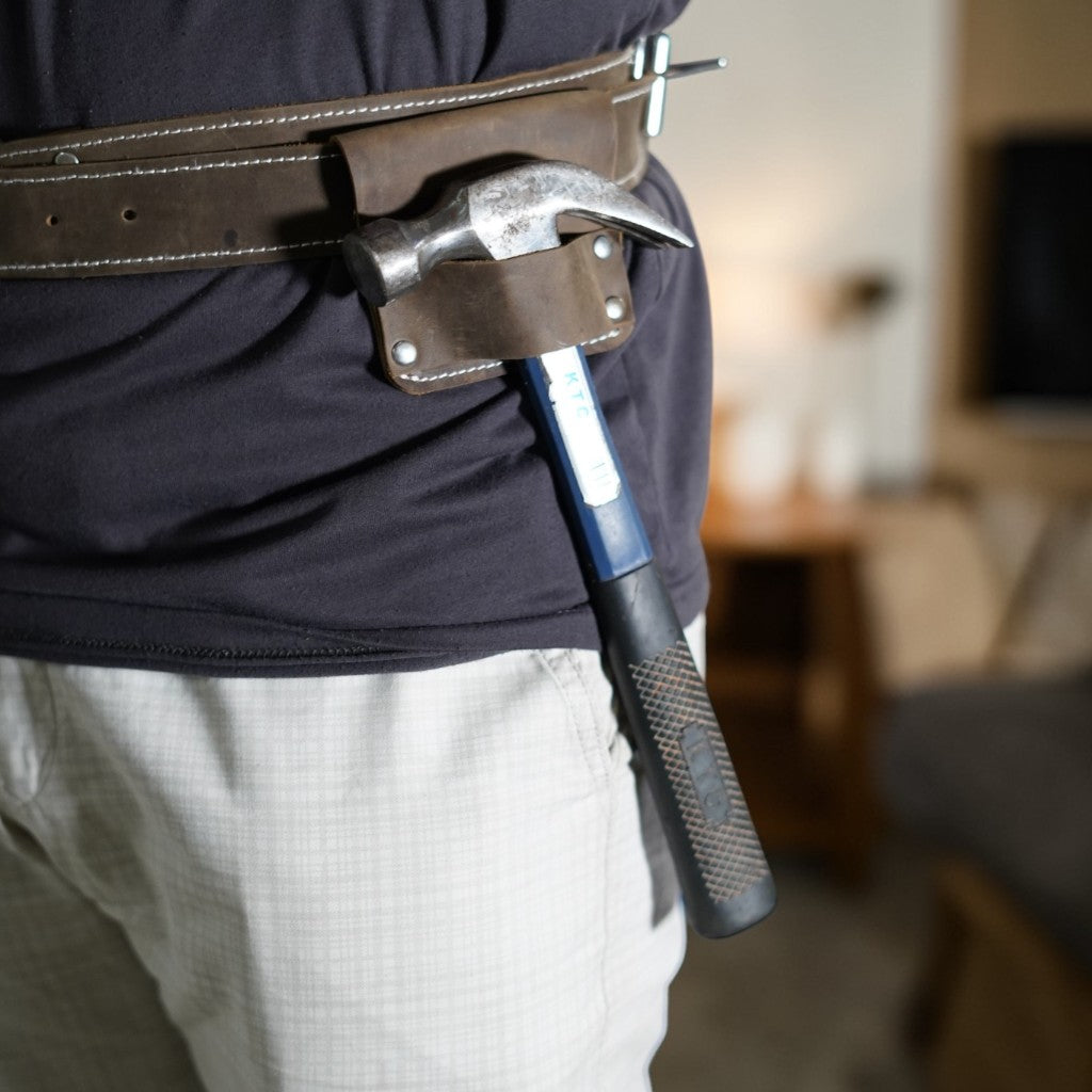 Person holding a large hammer with a blurred indoor background