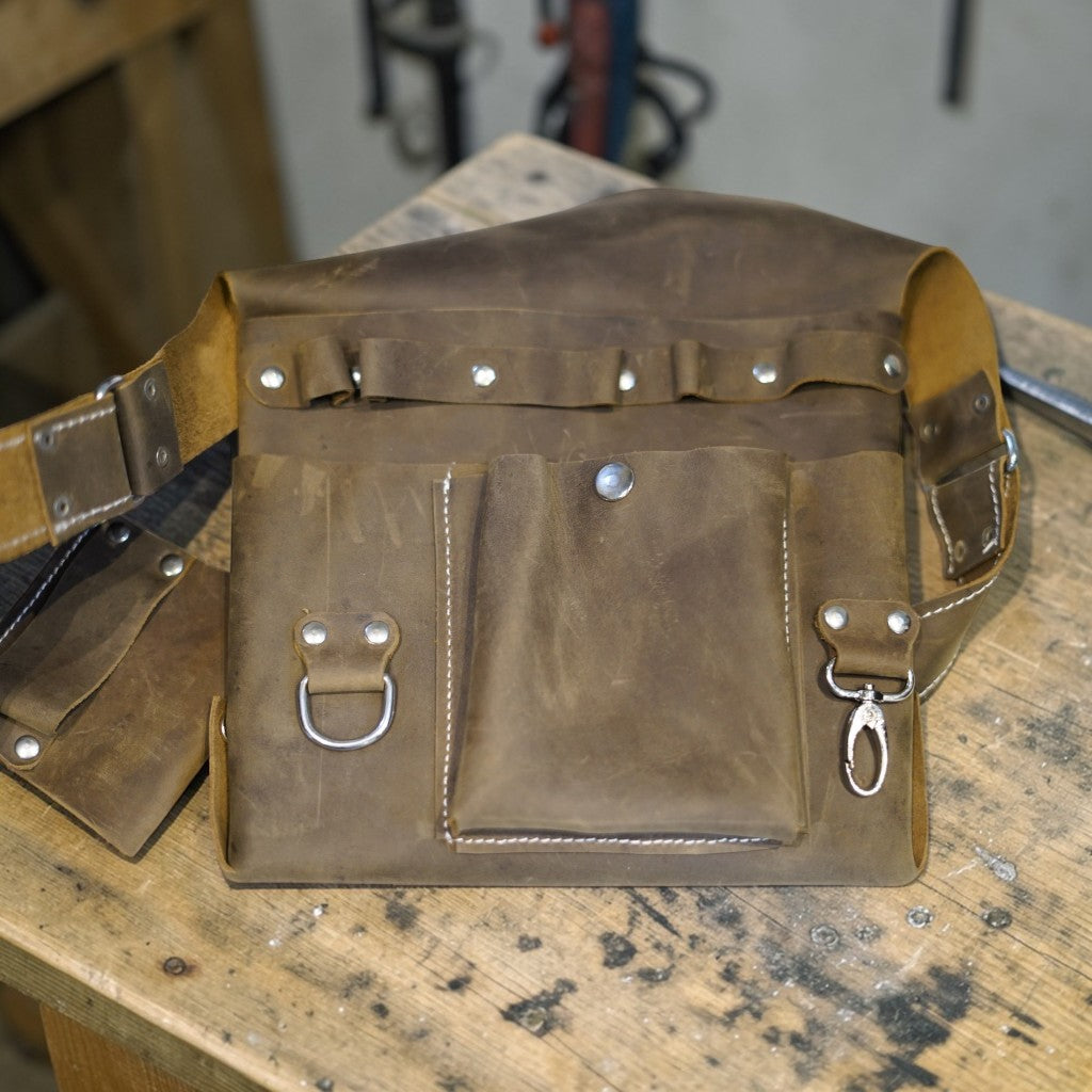 Brown leather bag with metal hardware on a wooden surface