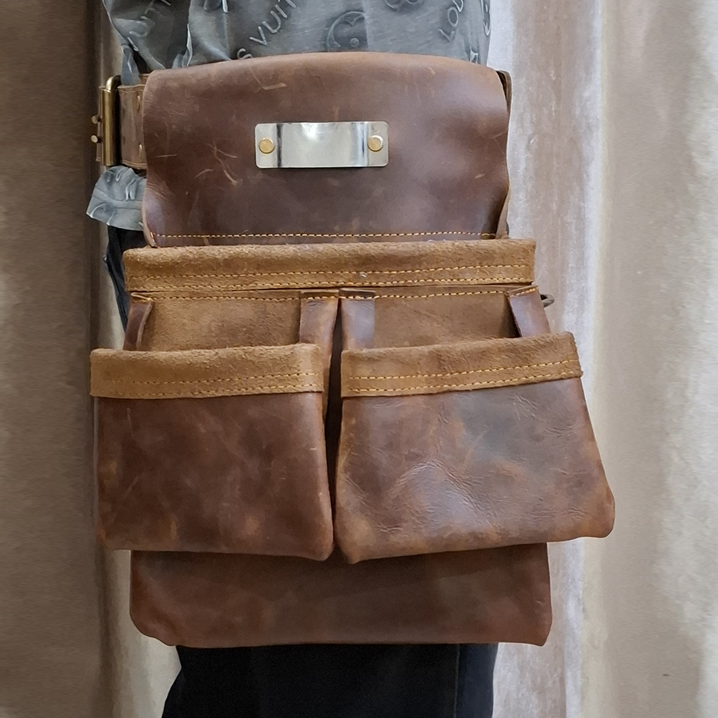 Brown leather tool belt with multiple pockets on a neutral background