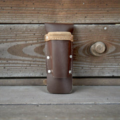 Brown leather holster with beige strap on a wooden background